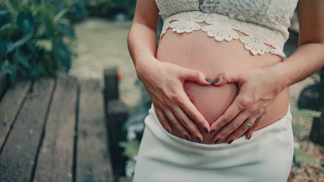 pregnant woman wearing white skirt holding her tummy